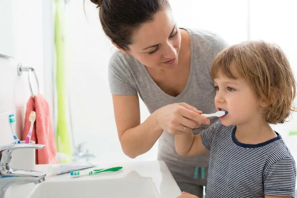 Child brushing teeth with parent